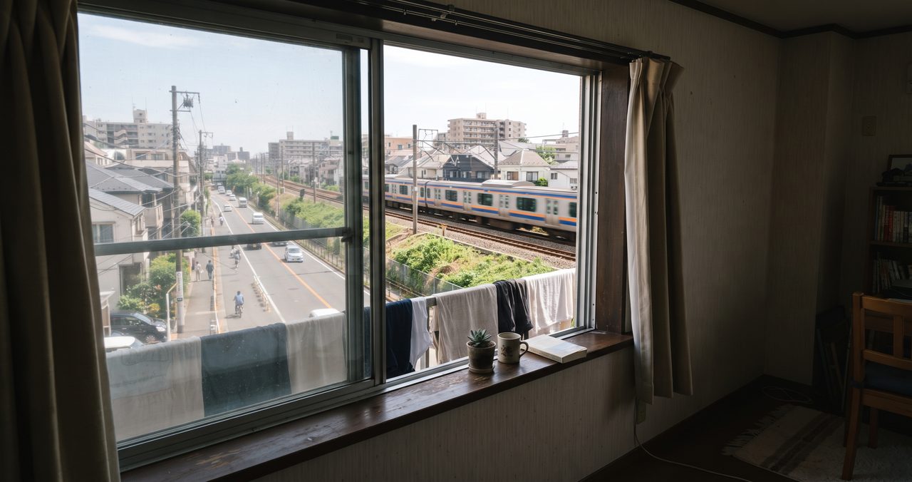 賃貸マンションの窓から見える周辺環境、道路と線路が近くにある住宅街の眺め